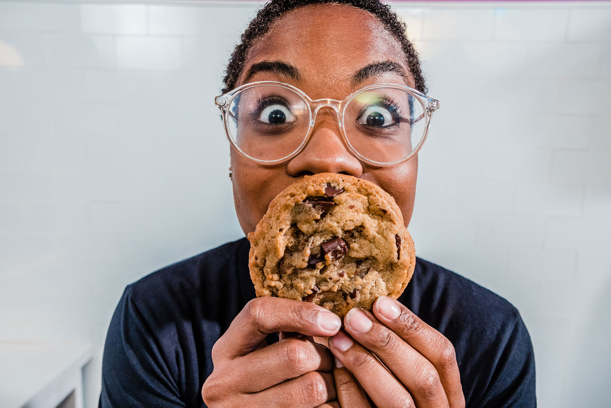 Person with glasses smiling behind a cookie